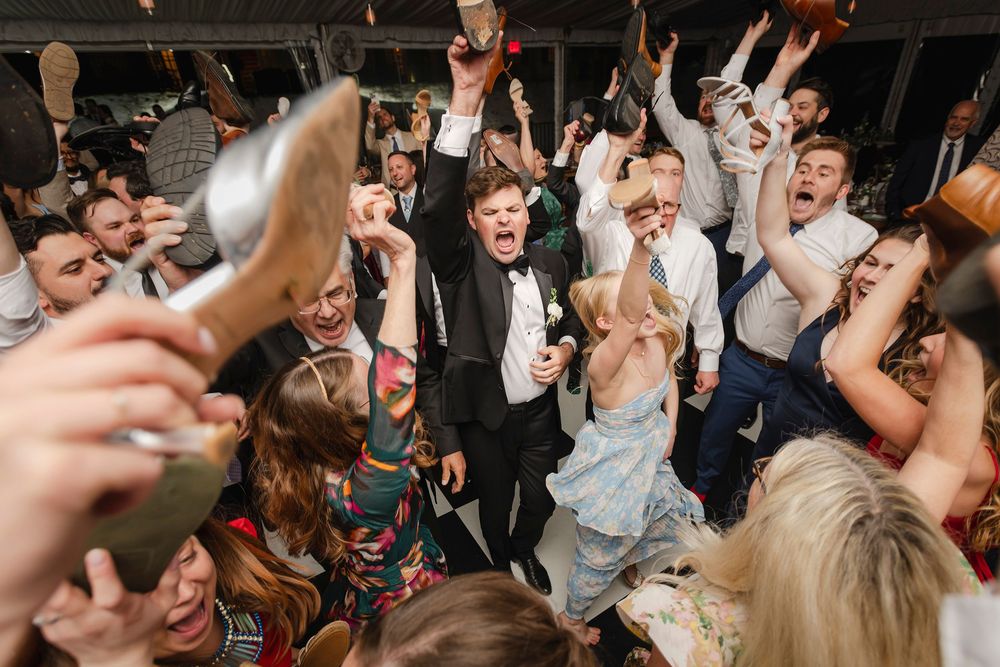 Joyful wedding reception guests dancing and celebrating on a crowded dance floor at an indoor party.
