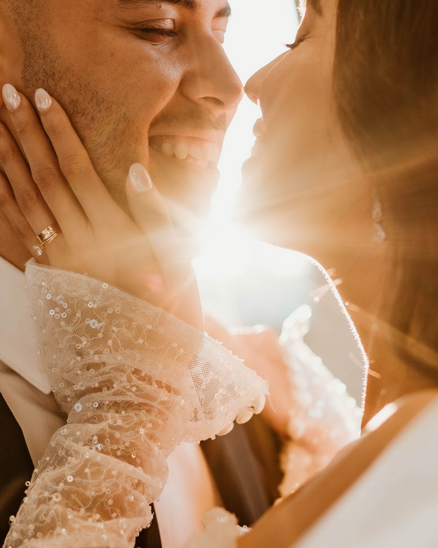 Tender moment between newlyweds illuminated by golden sunlight streaming through the window.
