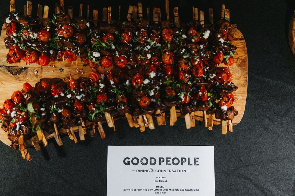 Bruschetta topped with cherry tomatoes and herbs on a wooden board at a Good People Dining event.