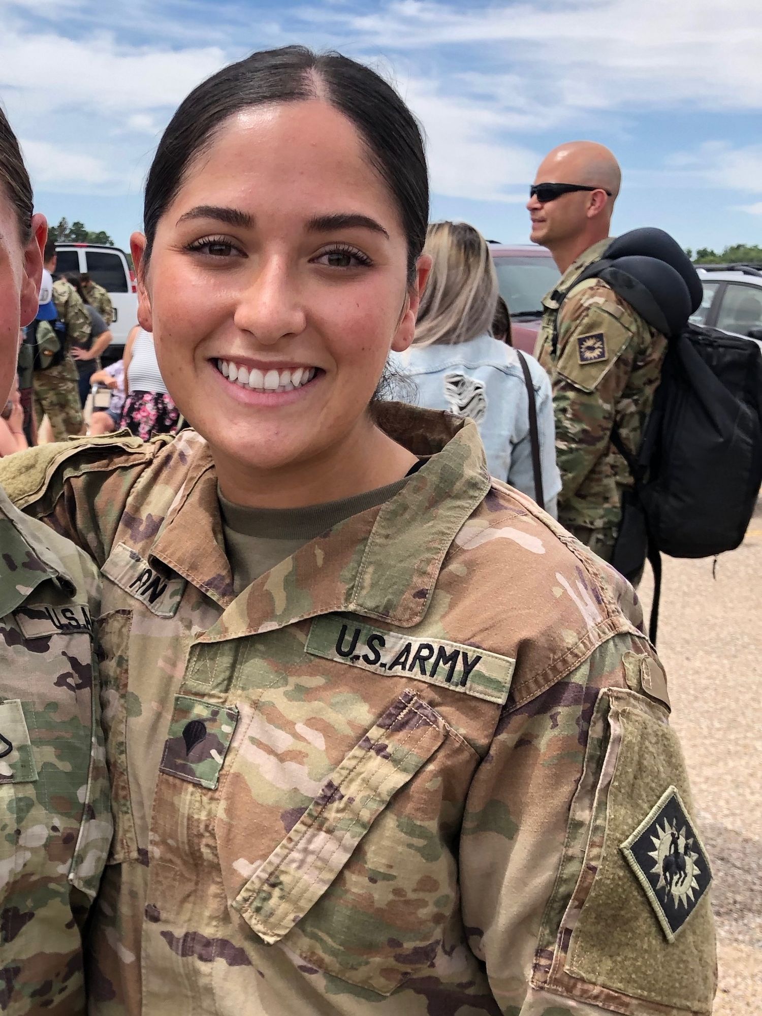 Female U.S. Army soldier in camouflage uniform standing attentively among fellow soldiers during military training.