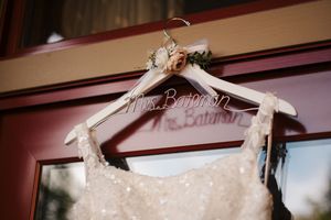 Personalized wedding dress hanger reading Mrs. Bateman with floral detail, holding a beaded bridal gown.