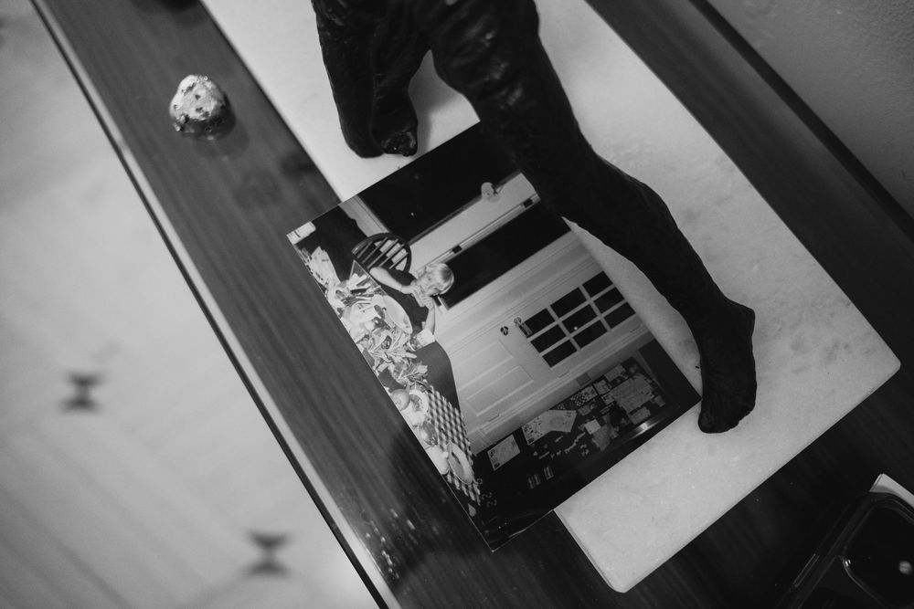 Black and white overhead shot of boots and a photo book on a wooden table before a wedding.