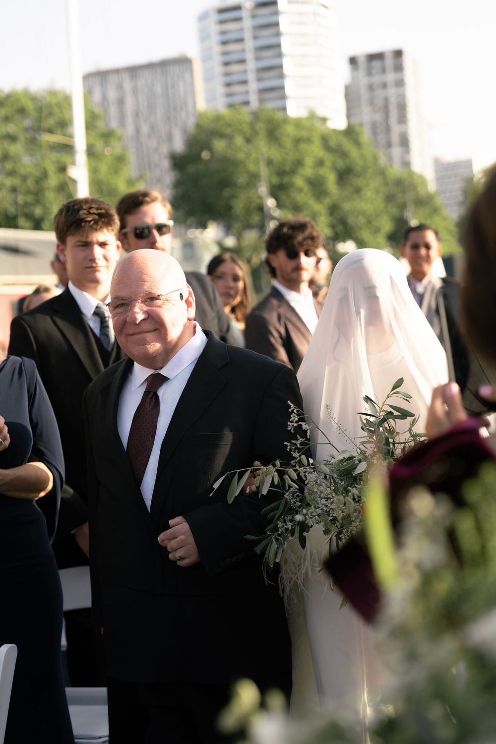 Father of the bride walks daughter down the aisle at outdoor urban wedding ceremony with guests. paris boat wedding ceremony, le clipper