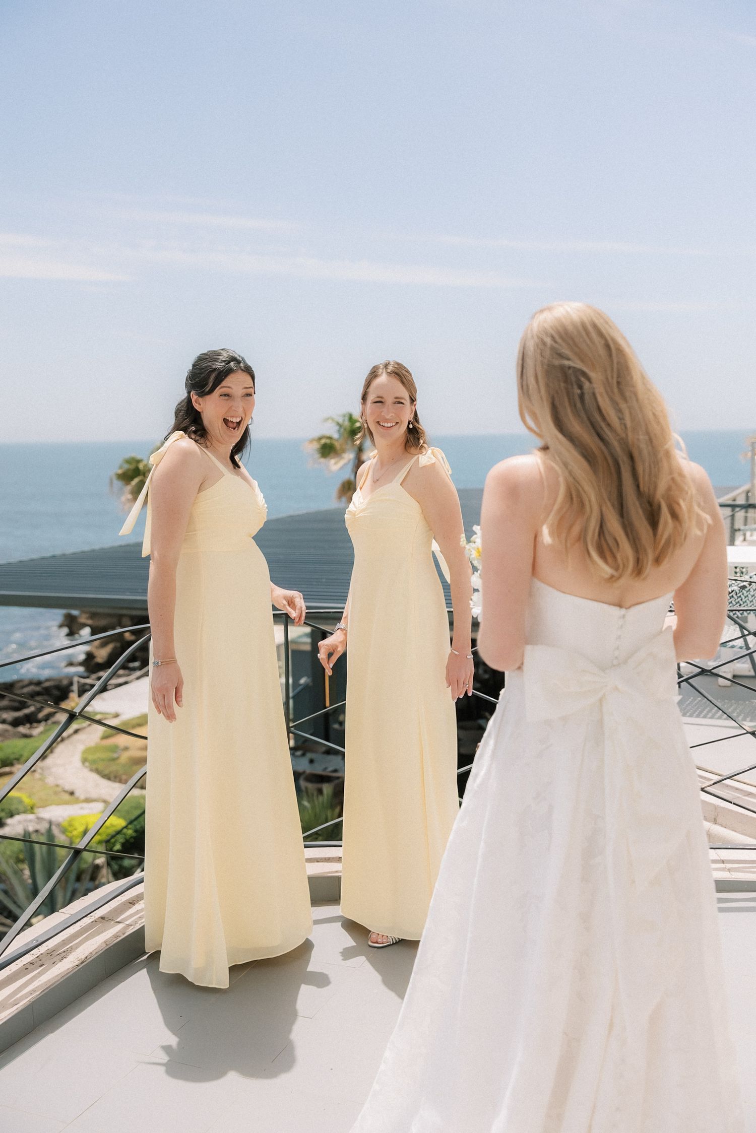 Bride sharing an emotional first look with her bridesmaids overlooking the Atlantic Ocean before her destination wedding in Cascais, Portuga