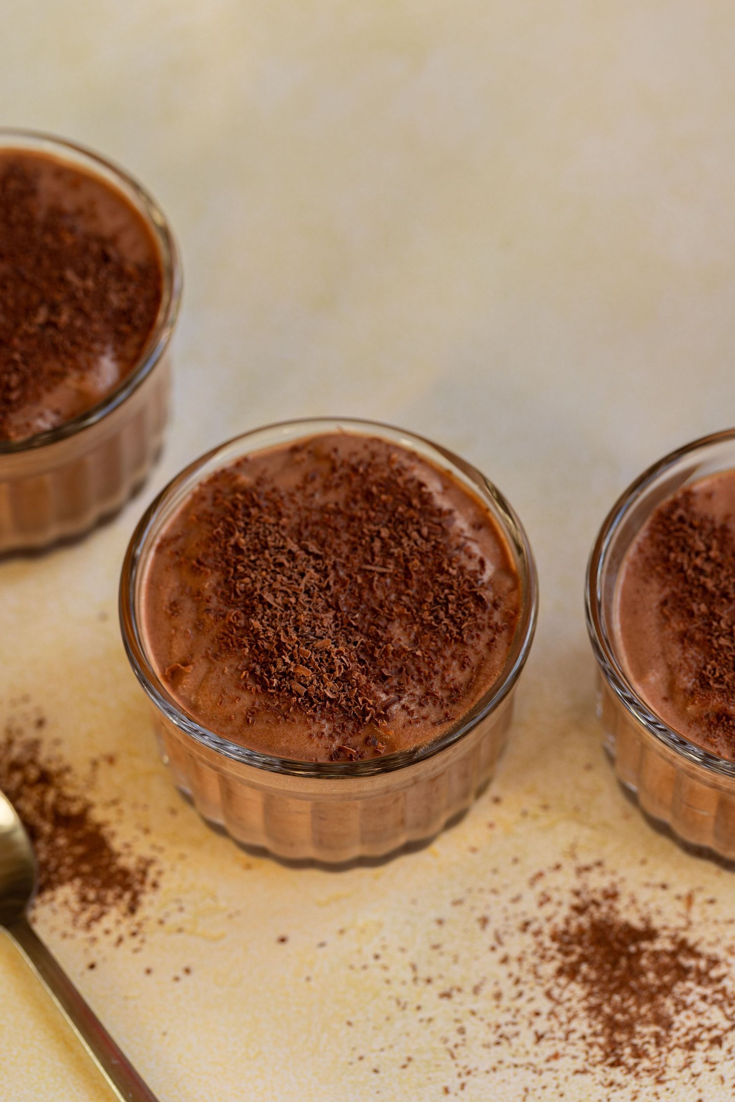 Close-up of chocolate mousse desserts in glass bowls with smooth and textured surfaces.
