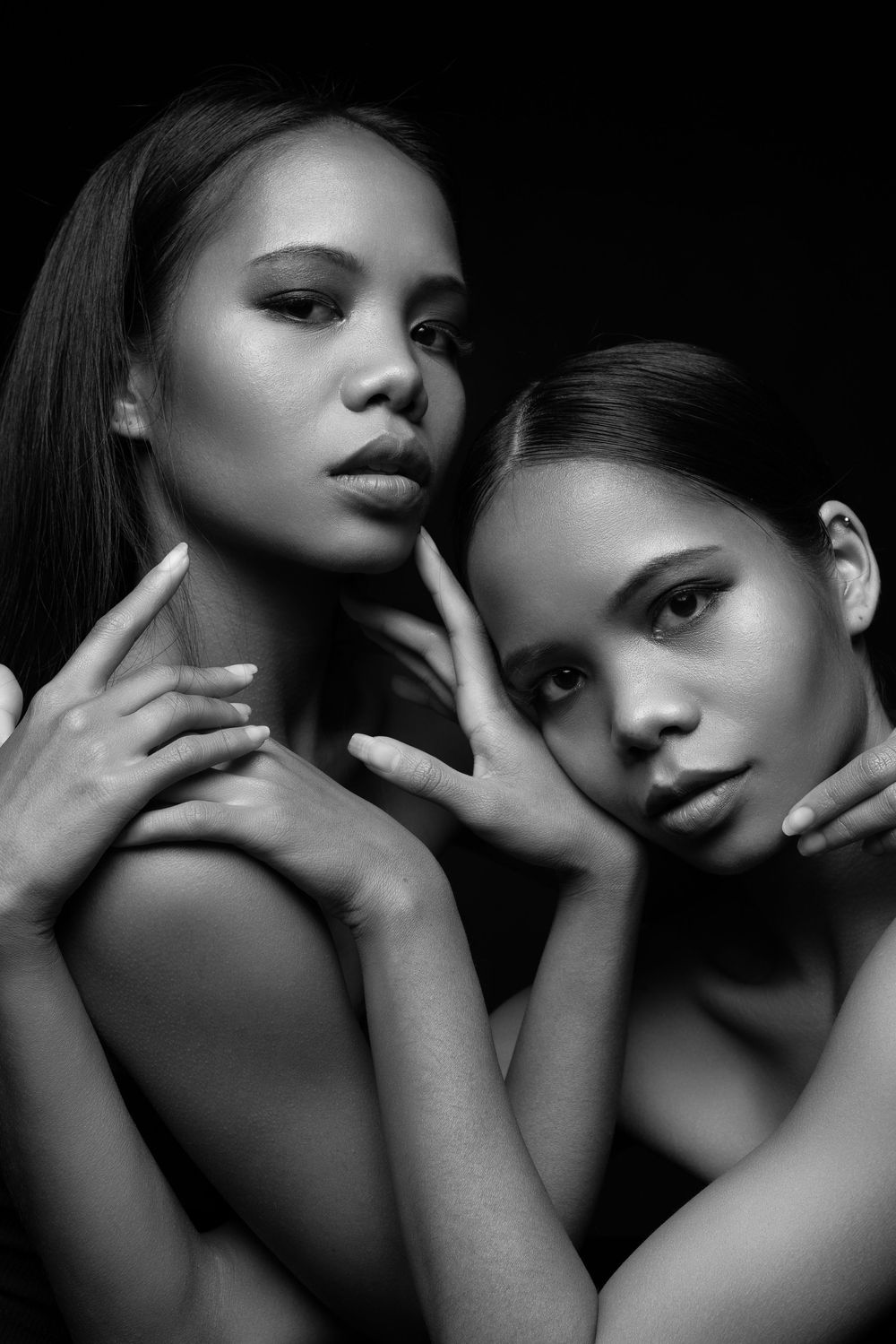 Black and white artistic portrait series showing intimate poses between two models in dramatic lighting.