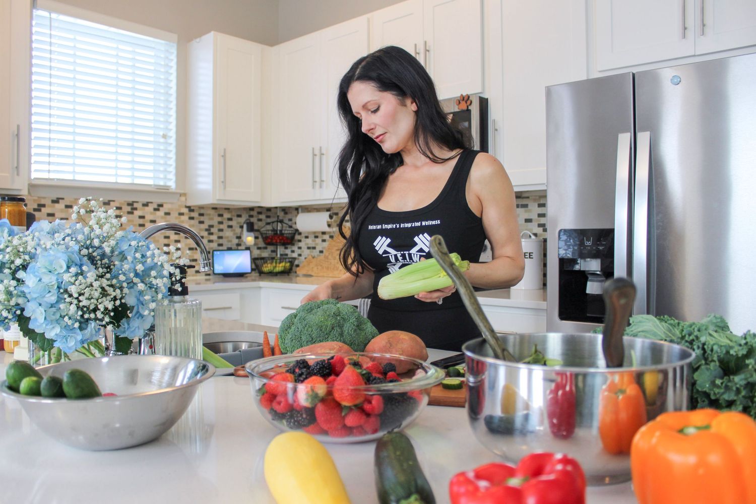 Woman preparing fresh vegetables in a bright modern kitchen with colorful produce on the counter.