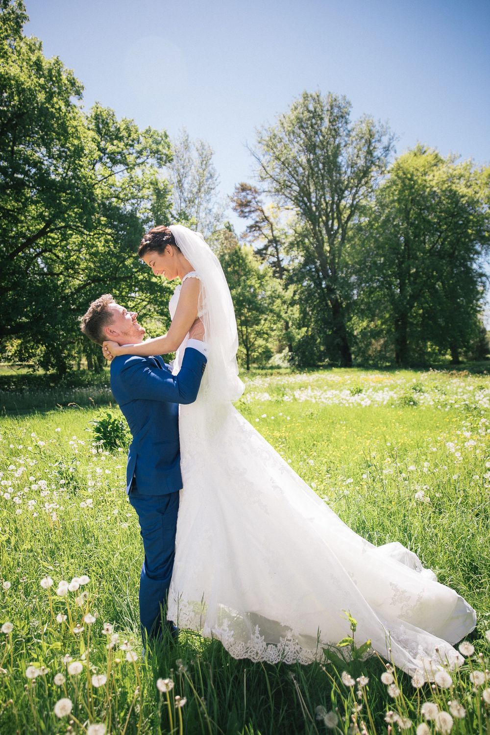 Brudgommen løfter bruden på en grøn eng – bryllupsfoto af Martin & Louise