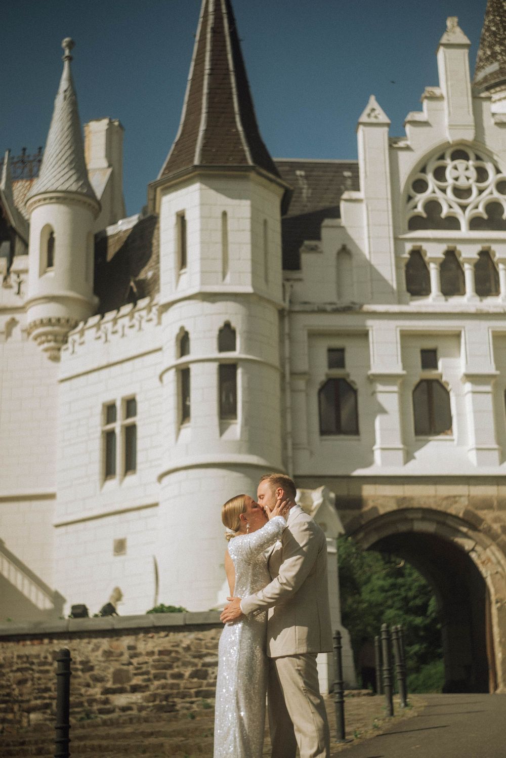 Bride and groom kissing in front of Schlosshotel Kommende Ramersdorf, Bonn with turrets on their wedding day.