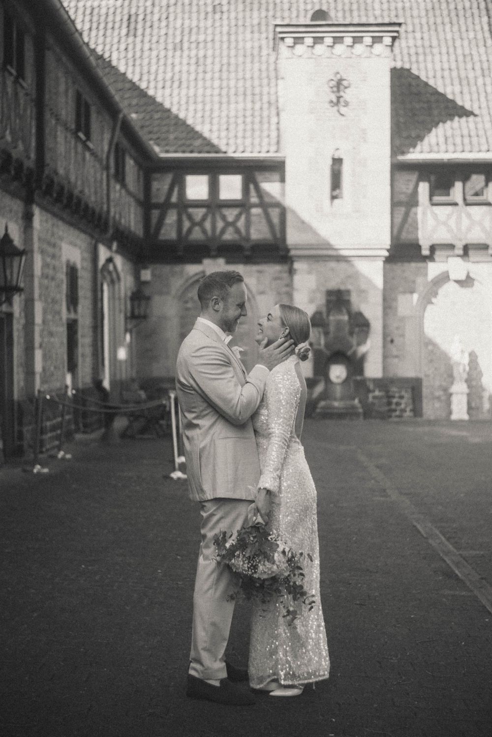 Black and white romantic wedding portrait of bride and groom about to kiss in front of historic building.