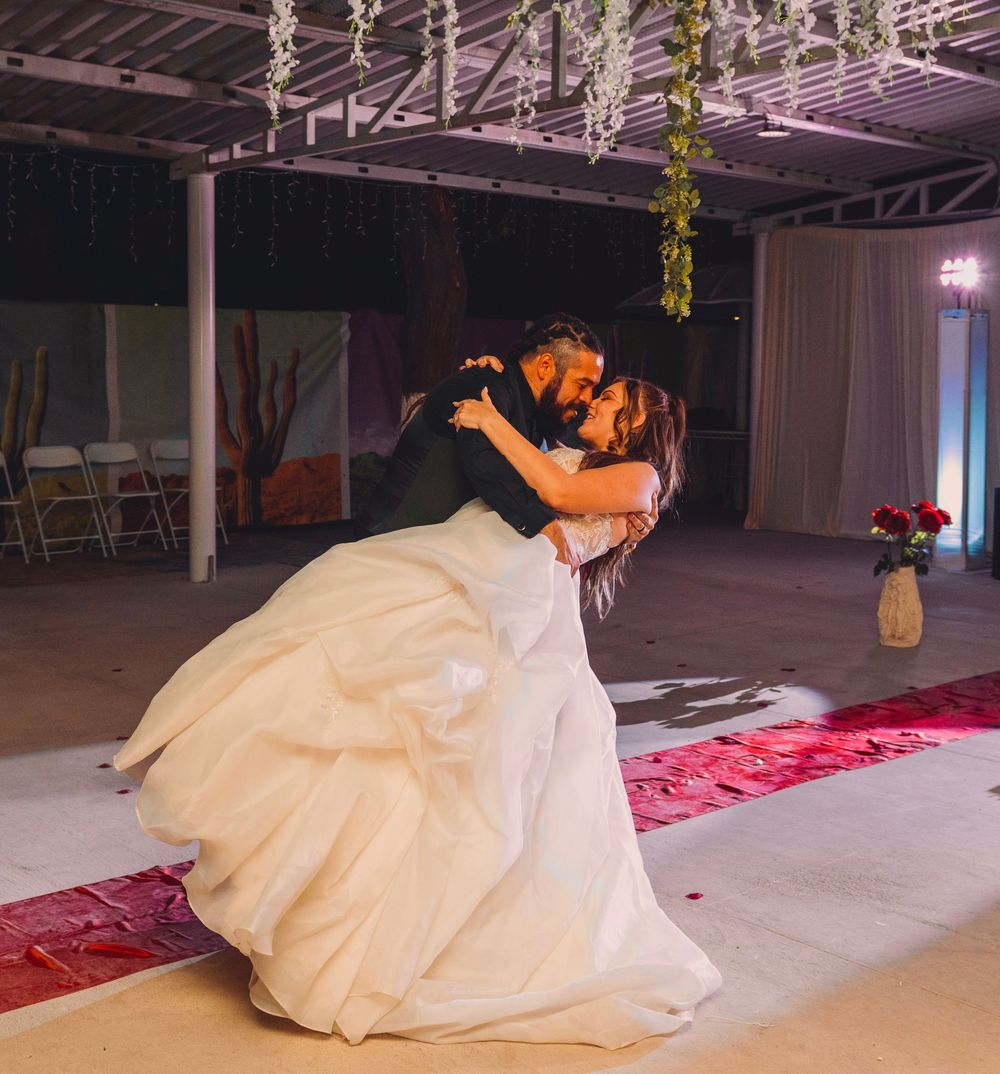 Bride and groom share a romantic dip kiss on the dance floor during their first dance at a wedding reception.