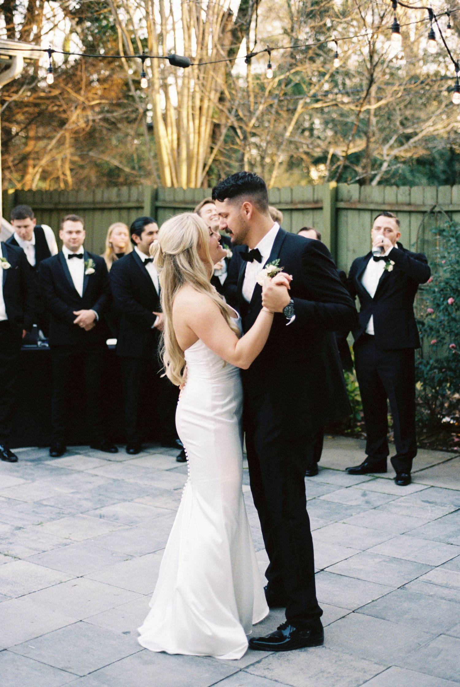 Bride and groom share first dance outdoors, surrounded by groomsmen in tuxedos at an elegant wedding reception at a Greensboro wedding venue