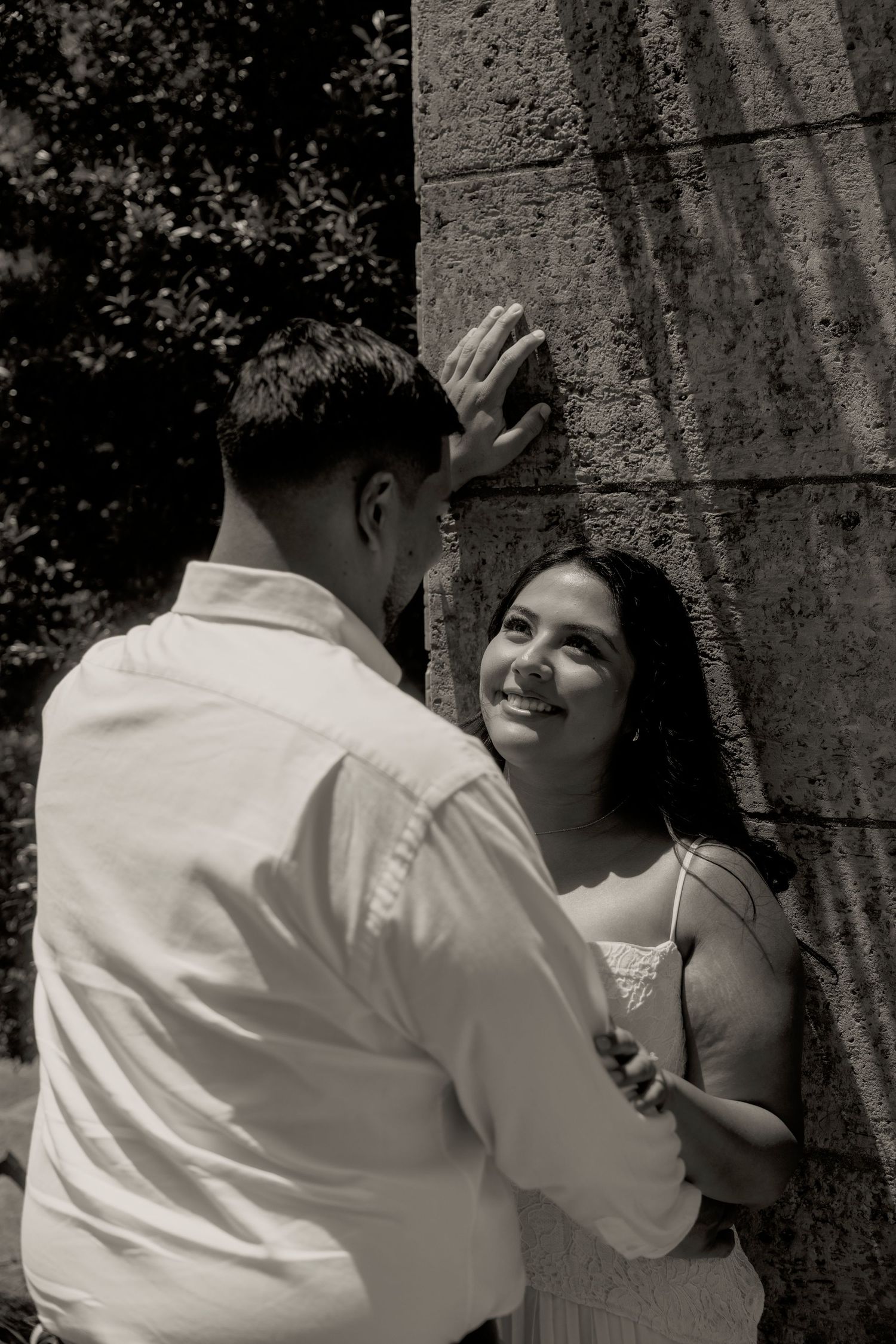 A couple smiling together in a black-and-white portrait.