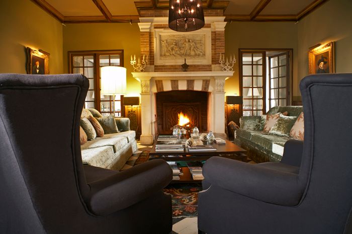 Salon chaleureux avec cheminée en pierre, fauteuils et canapés, dans une décoration intérieure de style classique.