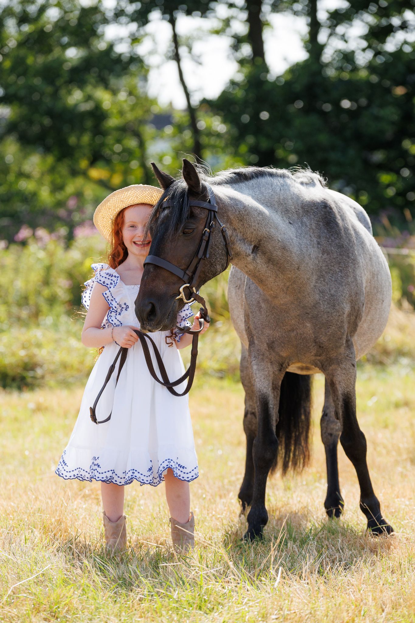 A smiling couple stands with a black and white horse and small dog in front of a white van on a farm.