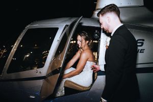 Elegant couple preparing to enter a private helicopter after their wedding celebration at night.