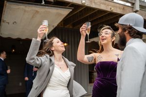 Wedding guests raise their glasses in celebration during a toast at an indoor reception venue.