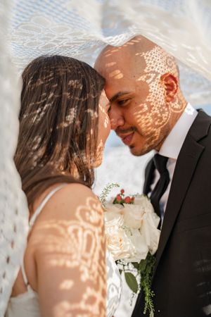 A romantic wedding photo with lace veil shadows creating delicate patterns in warm sunlight.