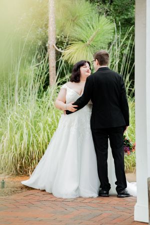 A bride and groom share an intimate moment together outdoors surrounded by tall grasses and palm fronds.