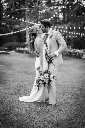 A romantic black and white wedding photo with string lights and a beautiful floral bouquet.