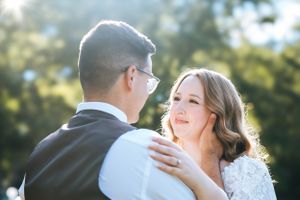 A couple shares an intimate moment while dancing together outdoors in soft sunlight.