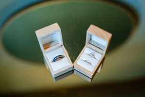 Two elegant wedding rings displayed in white boxes against a green-tinted background.