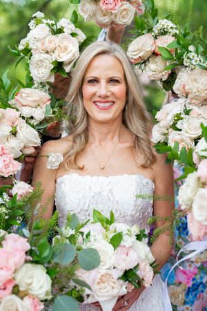 A floral wedding portrait featuring delicate pink and white roses with greenery in a romantic garden setting.