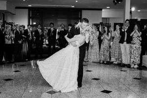 A black and white panoramic photo shows couples dancing at a formal wedding reception in an elegant ballroom.