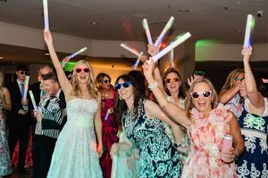 Wedding reception guests dancing and celebrating on a crowded dance floor with colorful lighting.