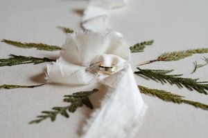 Close-up of white cotton balls with green fern leaves arranged on a light surface.