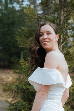 A joyful moment captured in a white wedding dress against a natural green backdrop.