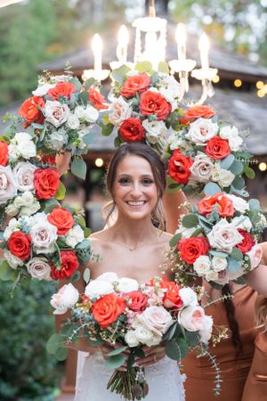 Beautiful wedding flowers featuring a floral arch with coral and white roses, candles, and a coordinating bridal bouquet.