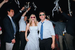 Wedding guests dancing and socializing at an evening reception with dark ambient lighting.