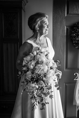 Black and white photo series of a bride in a wedding gown holding a romantic bouquet of roses and flowers.
