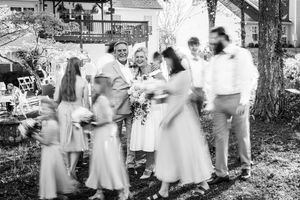 A group of people in white dresses and formal attire gather outdoors for what appears to be a vintage celebration.