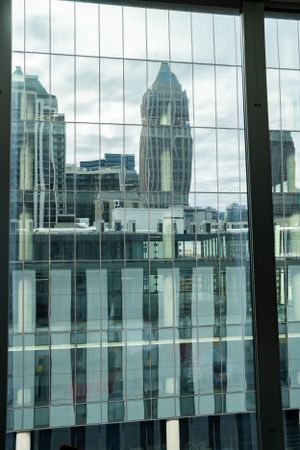 Modern city buildings with glass windows reflect against an overcast sky in an urban landscape.