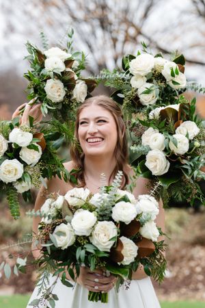 White roses and fresh greenery create lush wedding bouquets arranged in an elegant outdoor setting against natural backdrops.