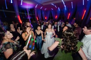 Wedding guests dance under vibrant purple and red neon lights at an energetic wedding reception party.