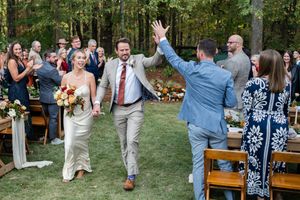 Wedding guests dance and celebrate together on a grassy lawn during an outdoor reception celebration.