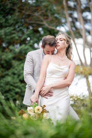 A tender romantic moment captured in a garden setting with soft natural lighting.