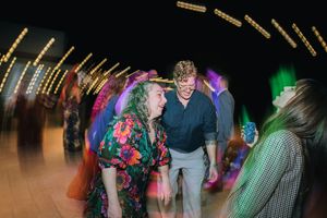 People dancing and socializing at a nightclub with colorful lighting and disco effects in the background.