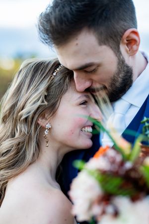 Close up portrait of newlyweds sharing an intimate moment outdoors with autumn foliage.