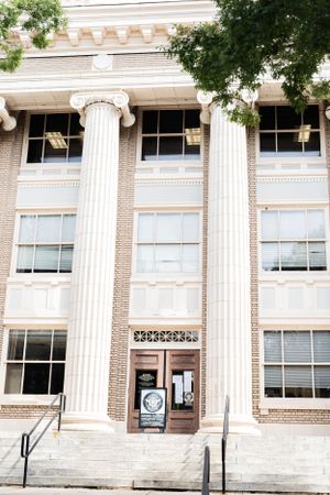 Classic brick building entrance with white Corinthian columns and tall windows showcases traditional academic architecture.