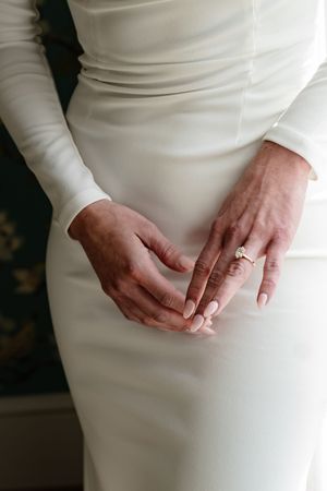 Close-up series of hands wearing an engagement ring against a white dress, showing different angles and poses.