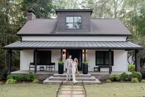 A modern white and gray craftsman style house with large windows and a covered front porch.