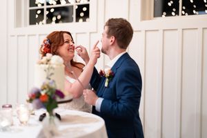 Bride and groom sharing a joyful cake cutting moment at their wedding reception.