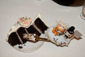 Slice of chocolate wedding cake with white frosting beside a bride and groom cake topper.