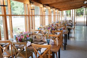 Elegant rustic wedding reception venue with long wooden tables set with colorful floral centerpieces.