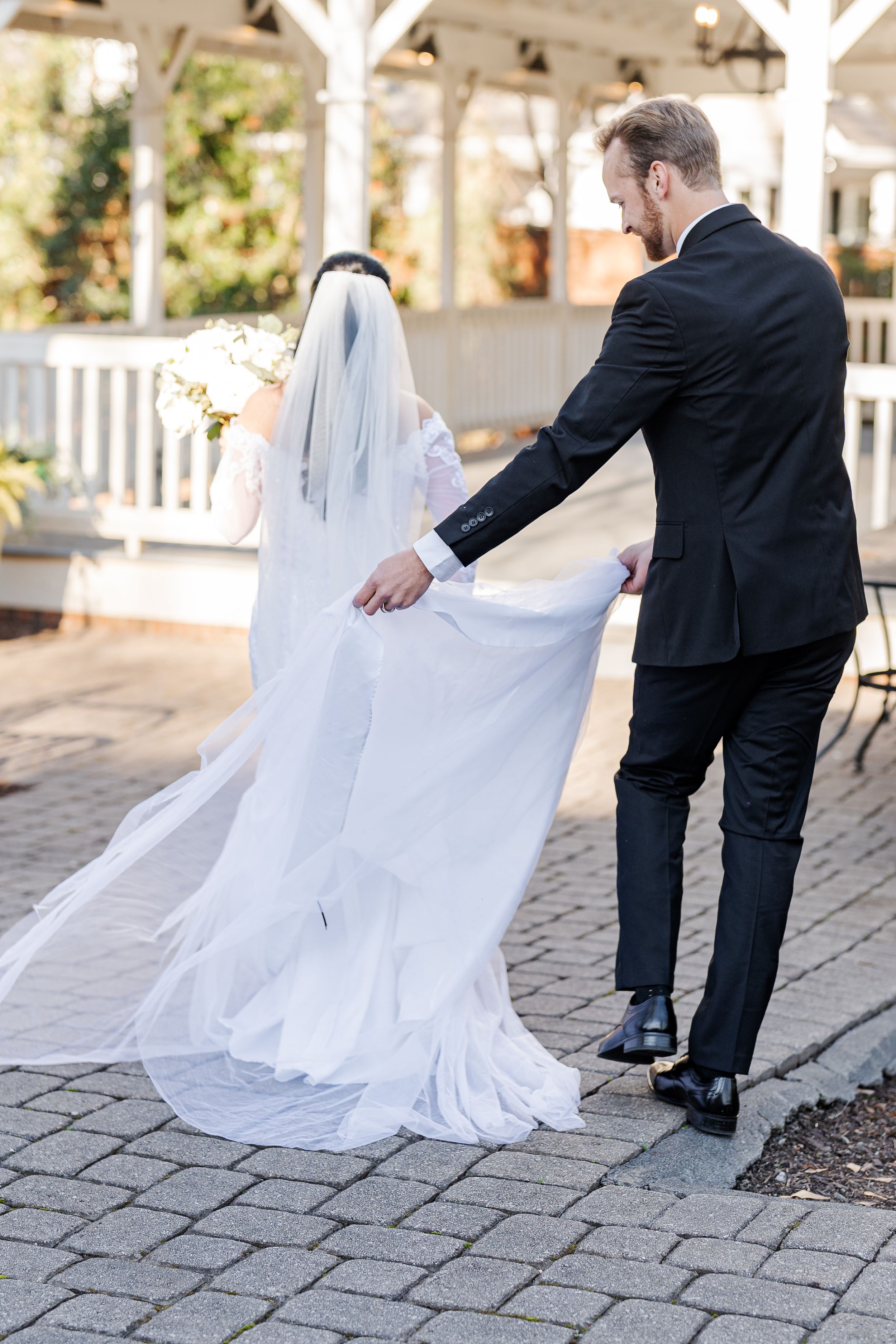 A sequence of photos showing a flowing white wedding dress being arranged on stone pavement during an outdoor photo session.