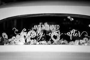 Black and white photo of a car window decorated with "And They Lived Happily Ever After" wedding decal.